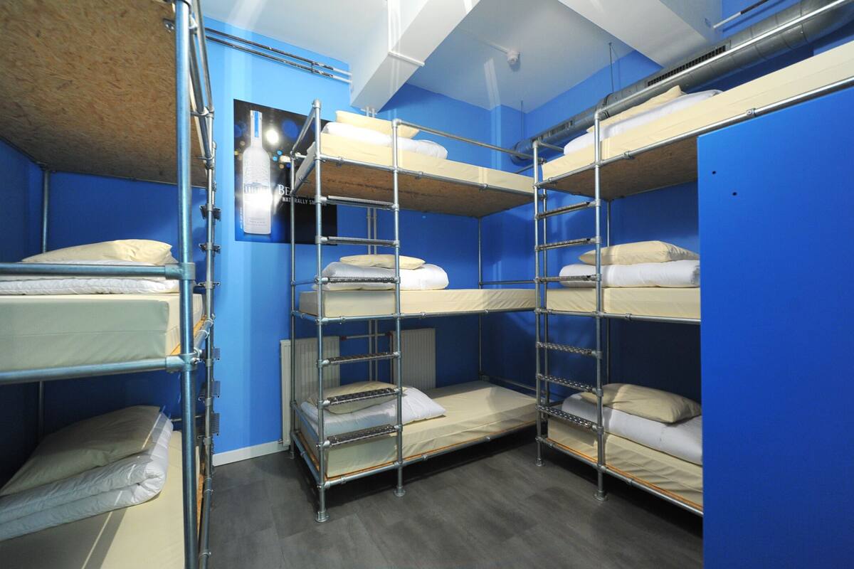 A bunk room with metal bunk beds, blue walls, and a wooden ceiling.