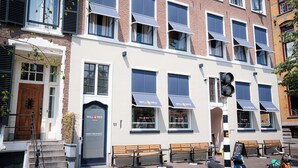 A building with multiple windows, a door, and benches outside. - Will & Tate City Stay (The Hague)