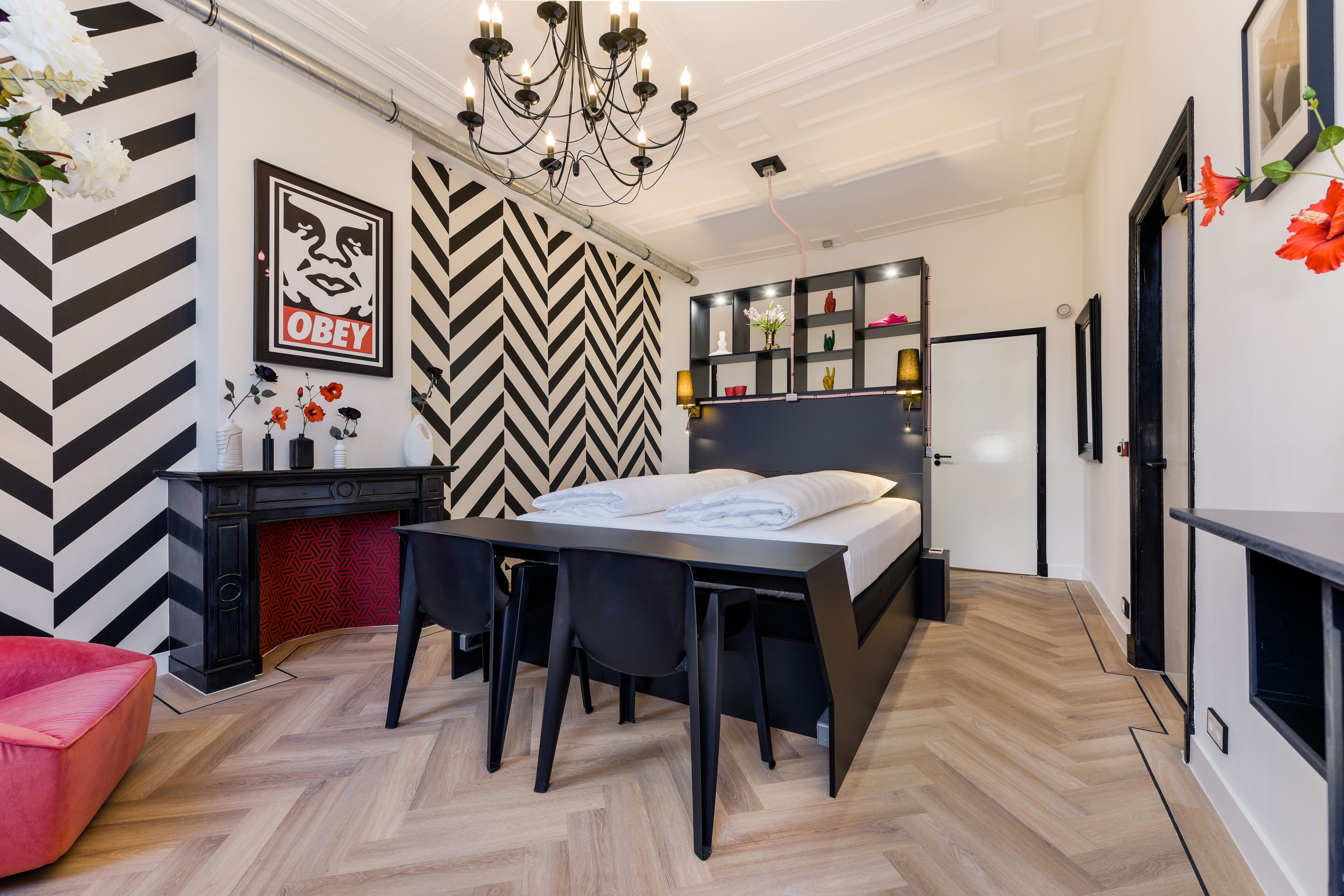 Quarto moderno com cama, escrivaninha e cadeira. Há um lustre sobre a cama e um espelho na parede.