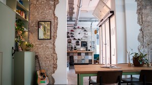 A rustic interior with exposed brick walls, a wooden dining table, and a guitar leaning against a cabinet. - Will & Tate City Stay (The Hague)