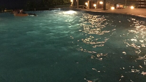 A nighttime view of a resort with a swimming pool, a large building with multiple balconies, and a view of the ocean. - Sea Rock Resort (Ko Pha-ngan)