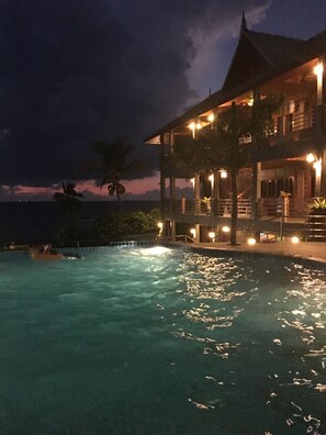 A nighttime view of a resort with a swimming pool, a large building with multiple balconies, and a view of the ocean. - Sea Rock Resort (Ko Pha-ngan)