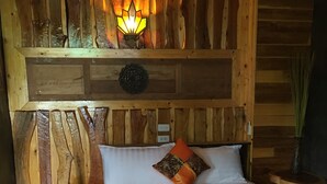 A wooden cabin room with a bed, a wall-mounted light, and a decorative wall panel. - Sea Rock Resort (Ko Pha-ngan)