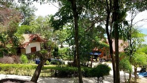 A tropical resort with lush greenery, a small building with a tiled roof, and a clear view of the sea. - Sea Rock Resort (Ko Pha-ngan)