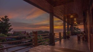A wooden balcony with a view of a sunset over a coastal landscape. - Sea Rock Resort (Ko Pha-ngan)