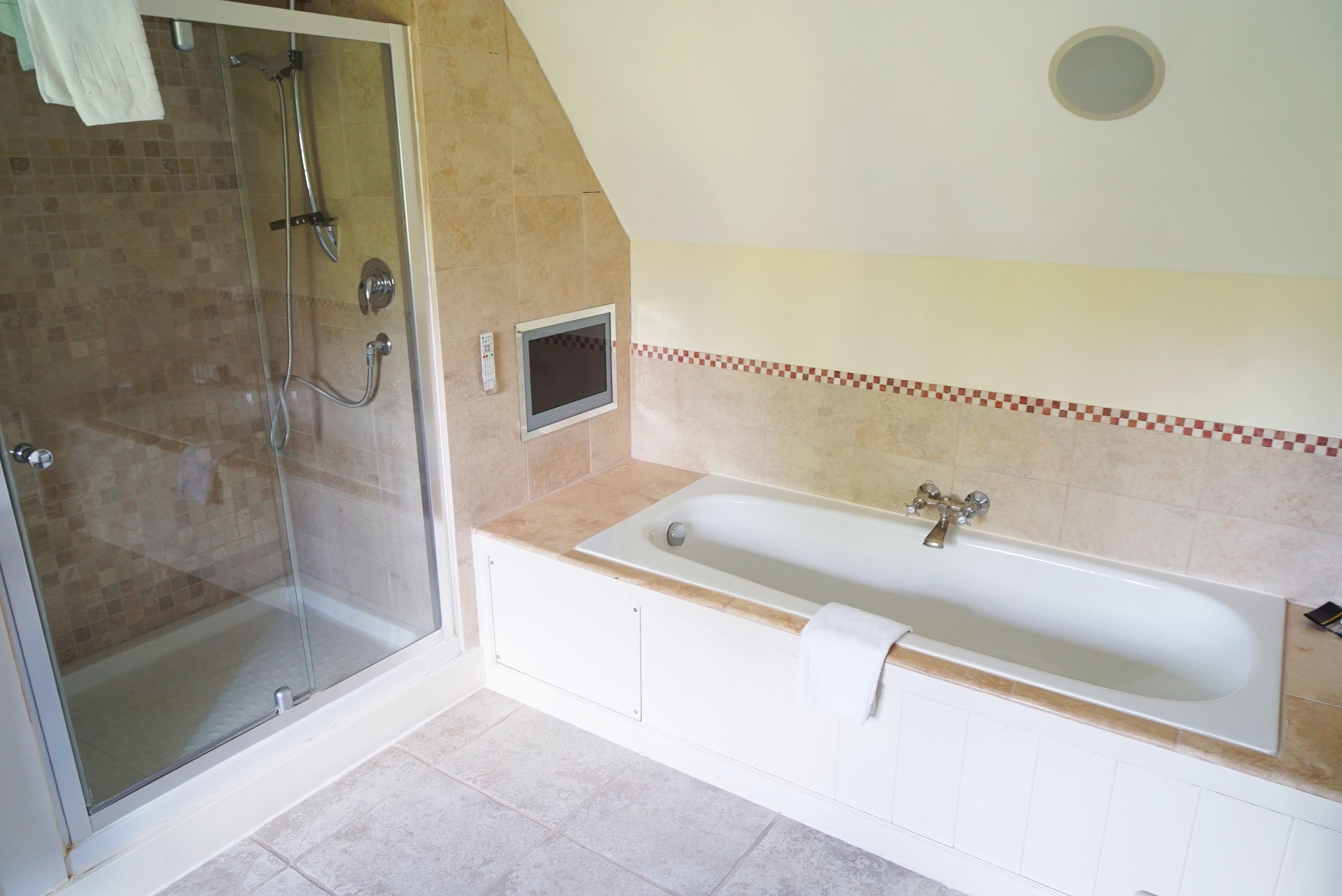 Ein Badezimmer mit einer gläsernen Duschkabine, einer freistehenden Badewanne und einer mit Fliesen verkleideten Duschwand.