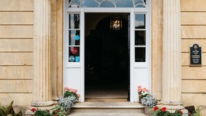 Indgangen til Cotswold House, med en klassisk arkitektonisk stil, der fremhæves af en markant indgang, søjler og et skilt, der viser, at det er ejendom til Rotary Club.