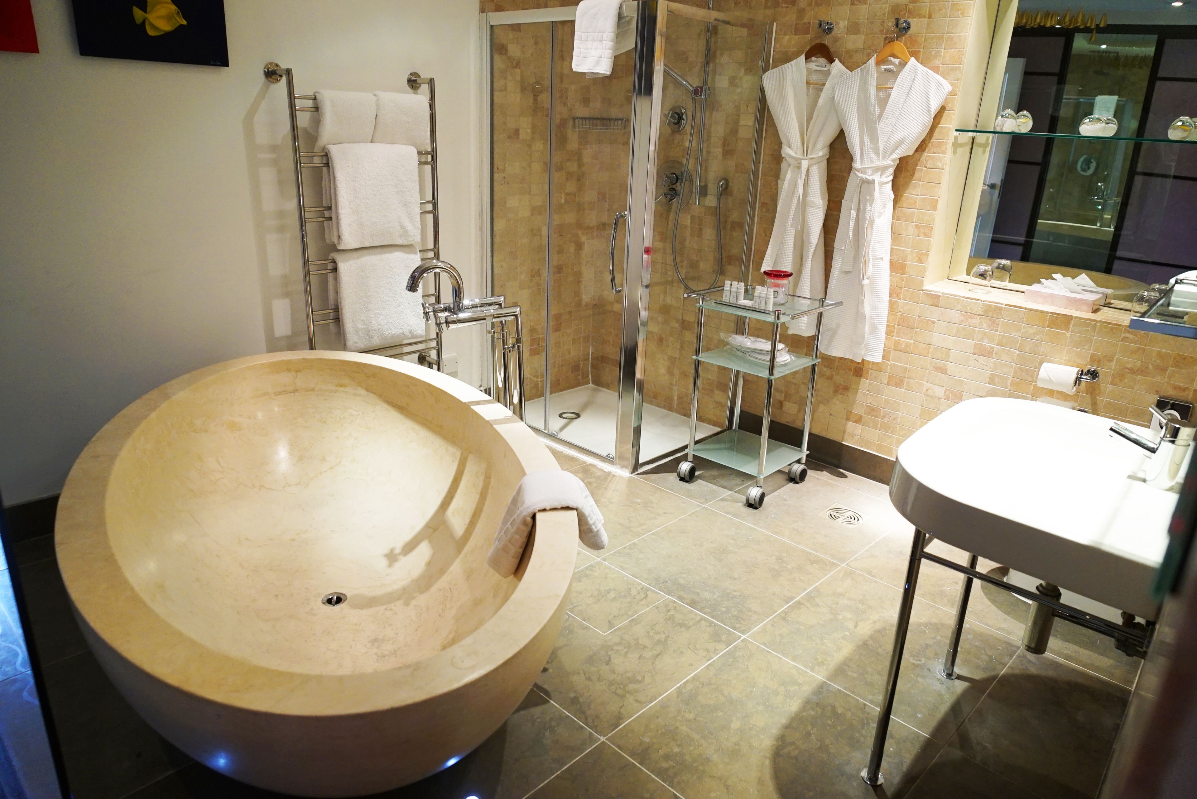 Ein modernes Badezimmer mit einer großen Holzbade Wanne, einer ein Glas abgeschirmten Dusche und einem separaten Waschbeckenbereich.