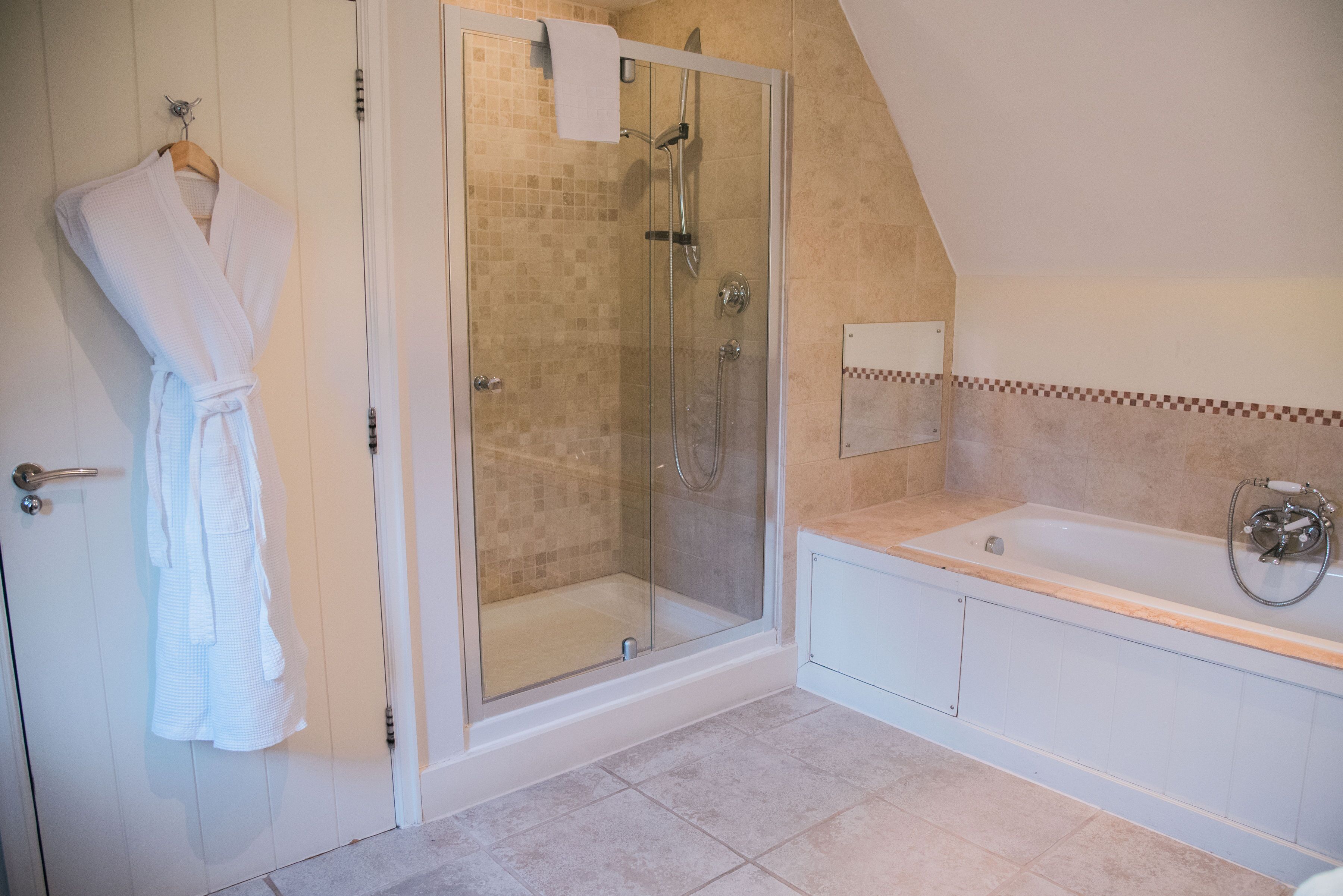 A bathroom with a glass-enclosed shower, a bathtub, and a towel rack with a white towel.