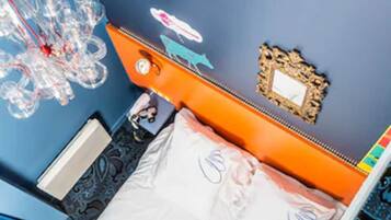 A room with a bed, a nightstand, a mirror, and a decorative wall piece.