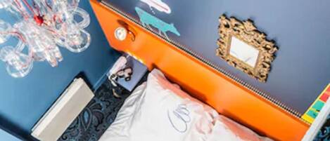 A room with a bed, a nightstand, a mirror, and a decorative wall piece.