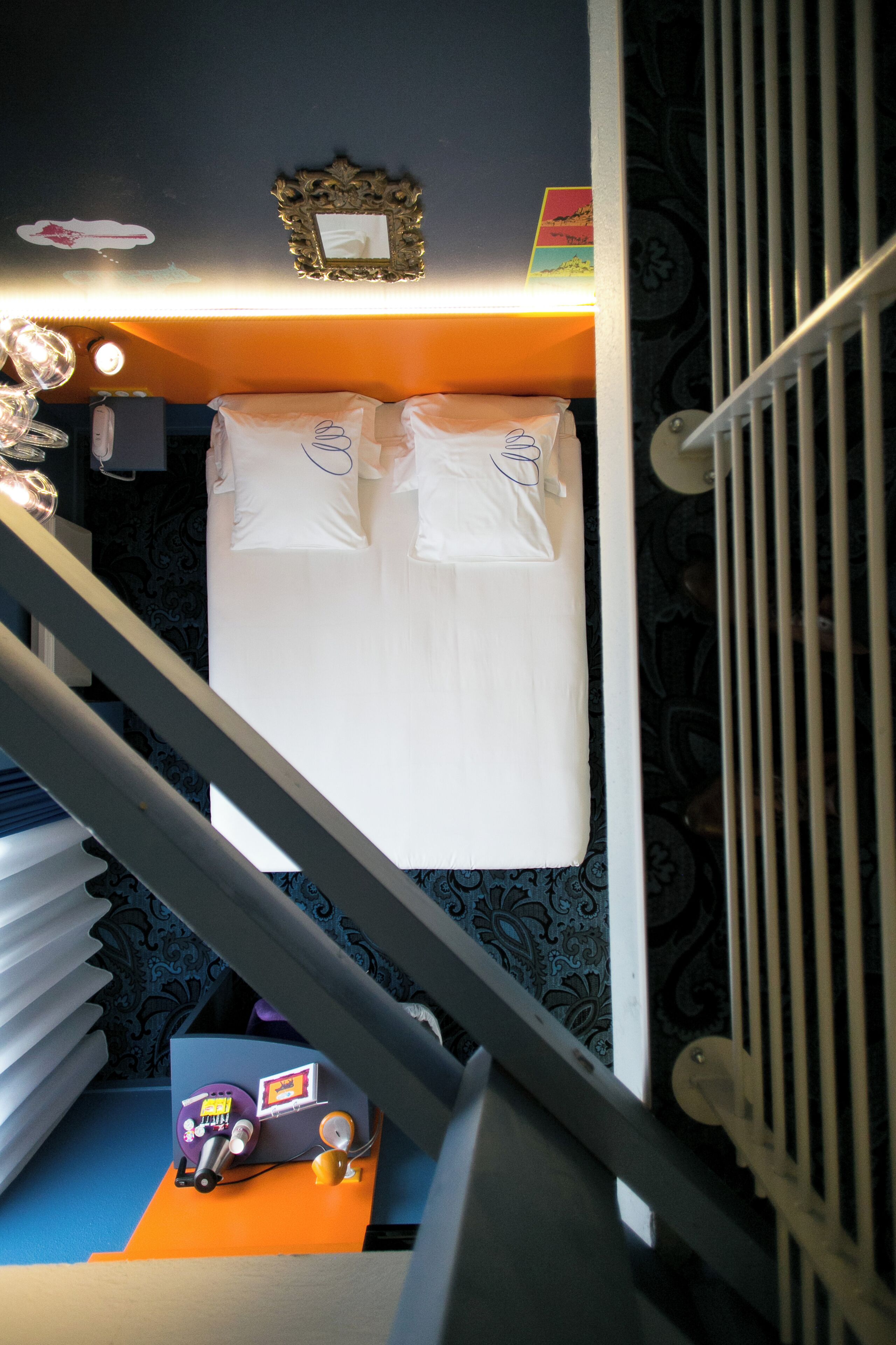 Un dormitorio con una cama, una mesita con lámpara y un cuadro colgado en la pared.