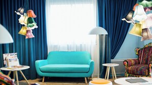 A room with a teal sofa, colorful hanging lamps, a patterned armchair, and a small round table with a lamp. - Hôtel Gabriel (Le Mont-Saint-Michel)