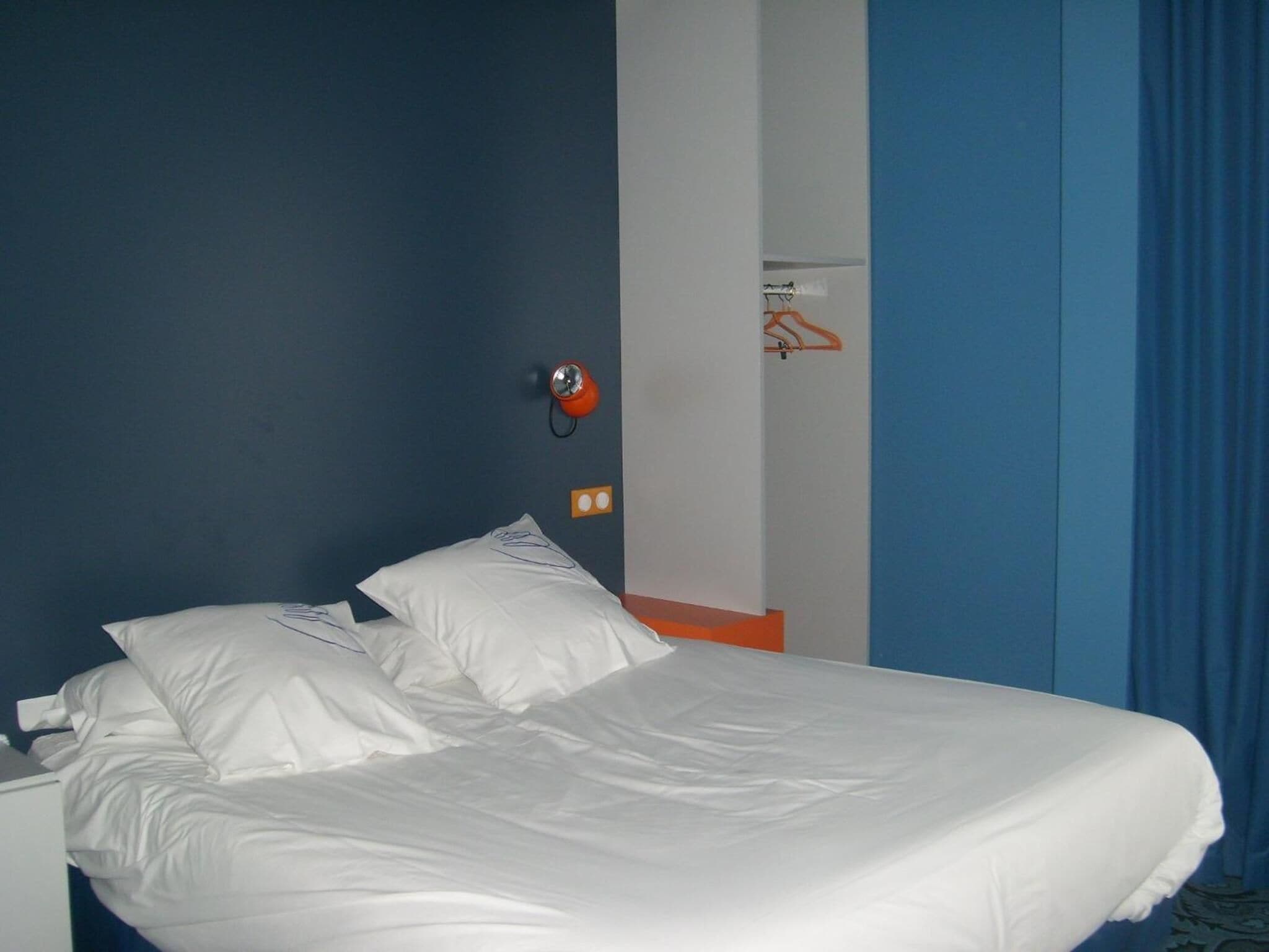 A bed with white linens in a room with blue walls and a white door.