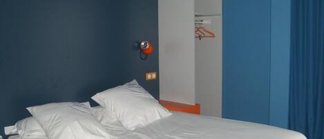 A bed with white linens in a room with blue walls and a white door.