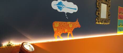 A wall with a decorative light strip, a wall-mounted mirror, and a wall decal of a bull.