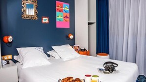A hotel room with a bed, breakfast tray, and a blue wall with decorative items. - Hôtel Gabriel (Le Mont-Saint-Michel)