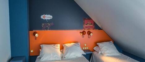 Una habitación con dos camas, una pared de acento azul, un reloj y luces fijadas a la pared.