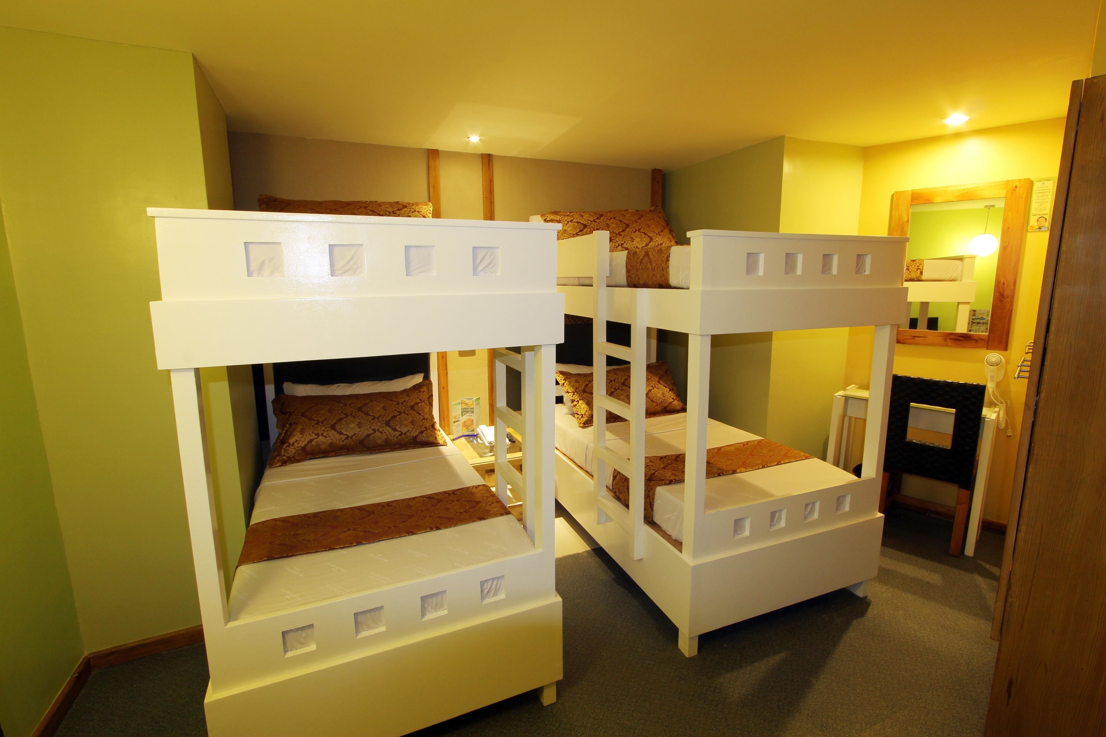 A room with bunk beds, a desk, and a mirror.