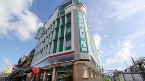 A multi-story hotel with a green and white facade, a prominent "BUROTE" sign, and a balcony with railings.