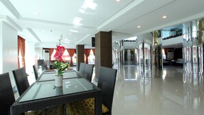 A spacious lobby with a glass-top table, wicker chairs, and a potted plant.