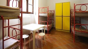 Een slaapzaal met stapelbedden, een klein tafeltje en een radiator.