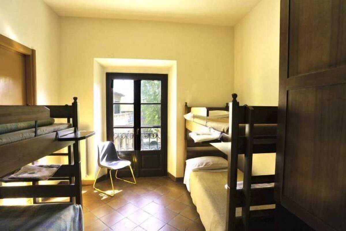 Ein Schlafsaalzimmer mit Stockbetten, einem Schreibtisch und einem Stuhl.
