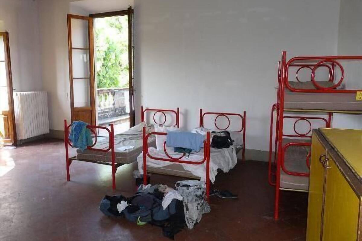 Ein Schlafsaalzimmer mit Etagenbetten, einem Heizkörper und einem Fenster mit Blick auf Grünflächen.
