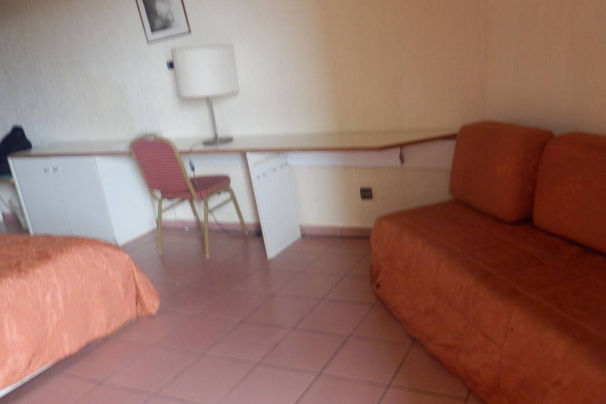 A room with a bed, a desk with a chair, and a sofa.