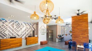 Un espace d’accueil moderne avec des comptoirs de réception en bois, un coin salon bleu et des panneaux muraux décoratifs.