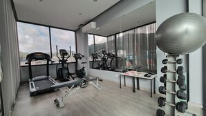 Une salle de sport moderne équipée de machines de cardio, d’un banc de développé couché et d’une série de haltères.