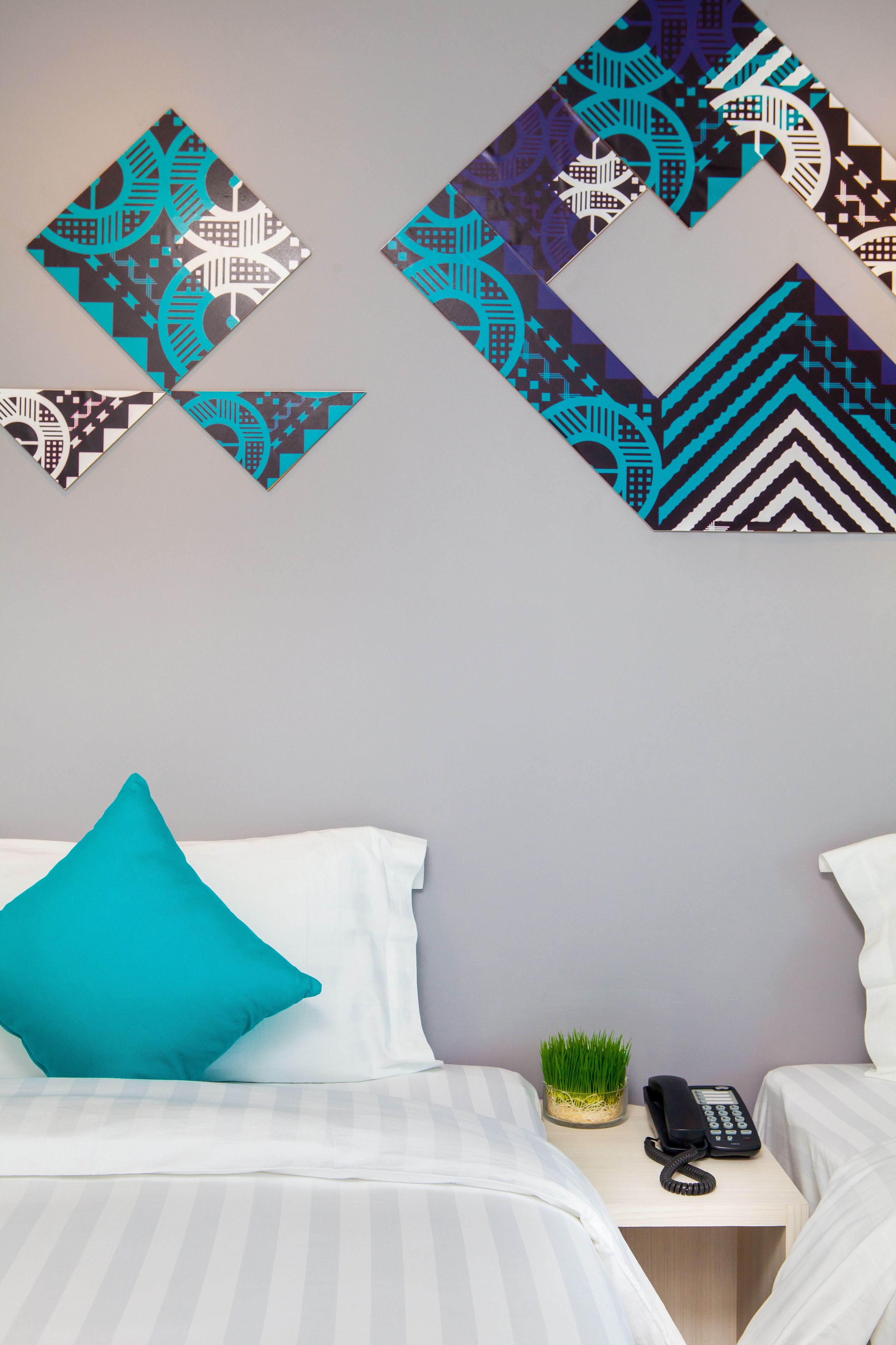 A hotel room with a bed, a nightstand with a phone, and decorative wall art.