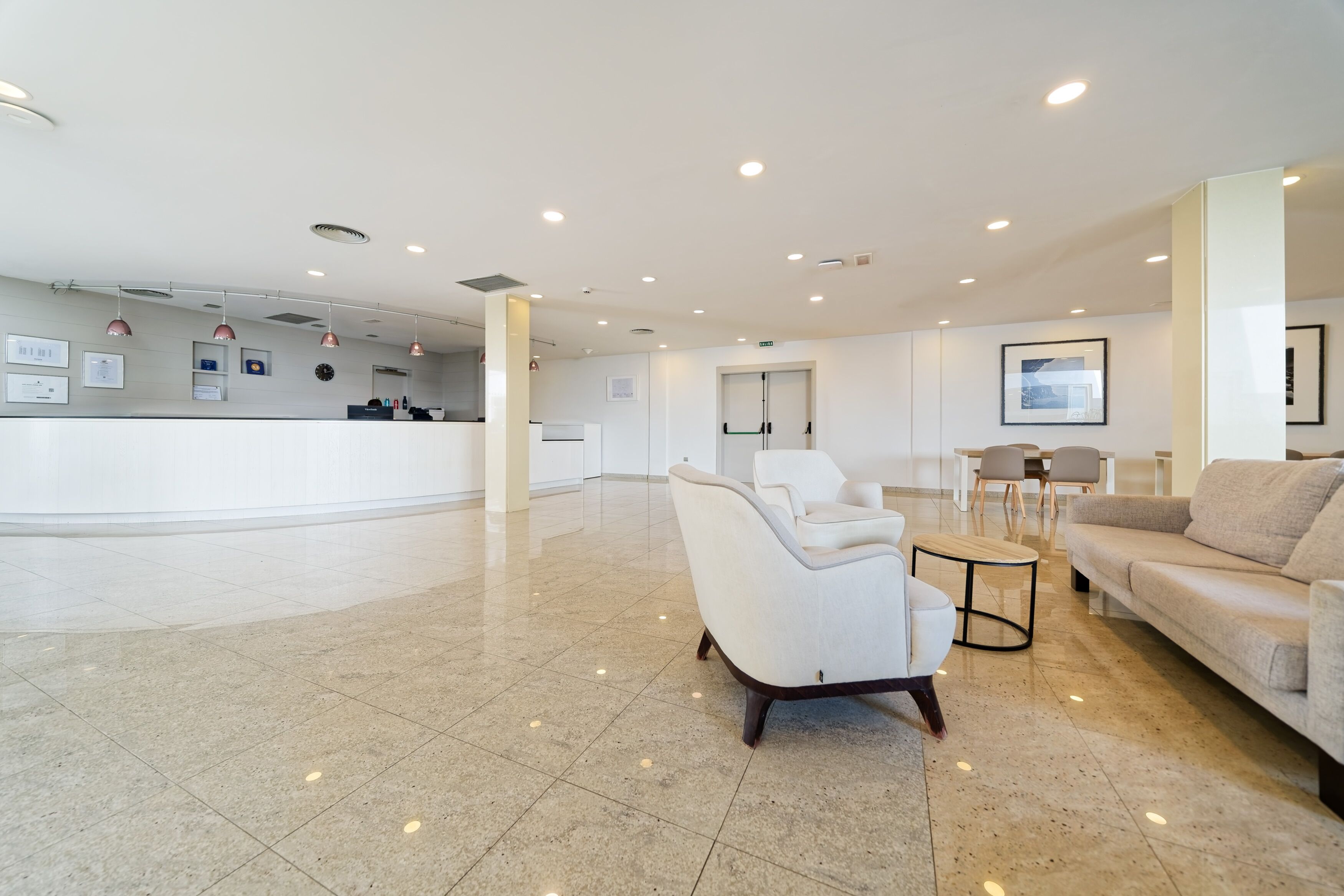 Amplio vestíbulo con mostrador de recepción, zona de estar y puerta que conduce a otra habitación.