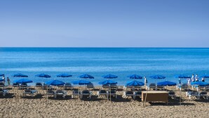 A beach with rows of blue umbrellas and white lounge chairs. - Hotel Floresta (Tías)