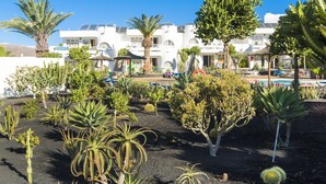 A hotel with multiple white buildings, a garden with various plants, and a pool area. - Hotel Floresta (Tías)