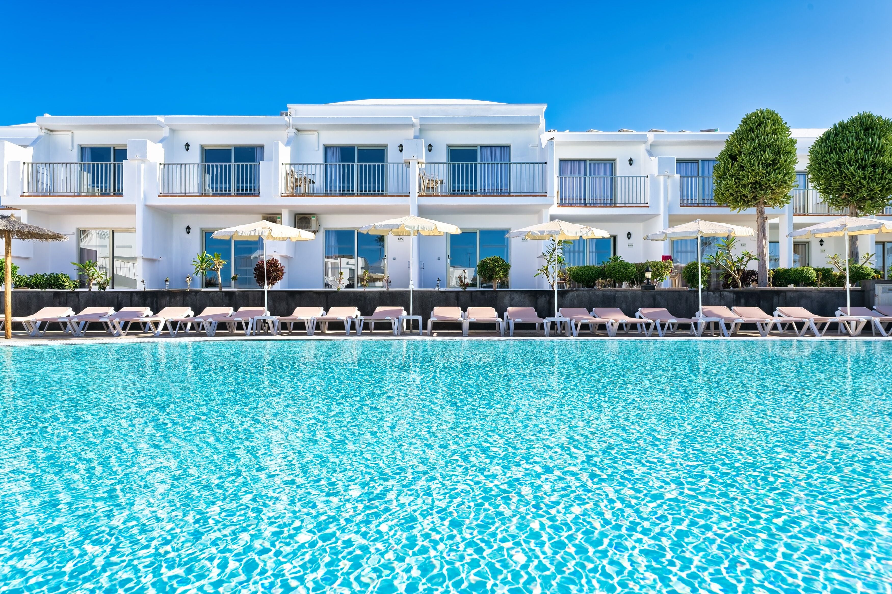 Un hotel con piscina, tumbonas y sombrillas.