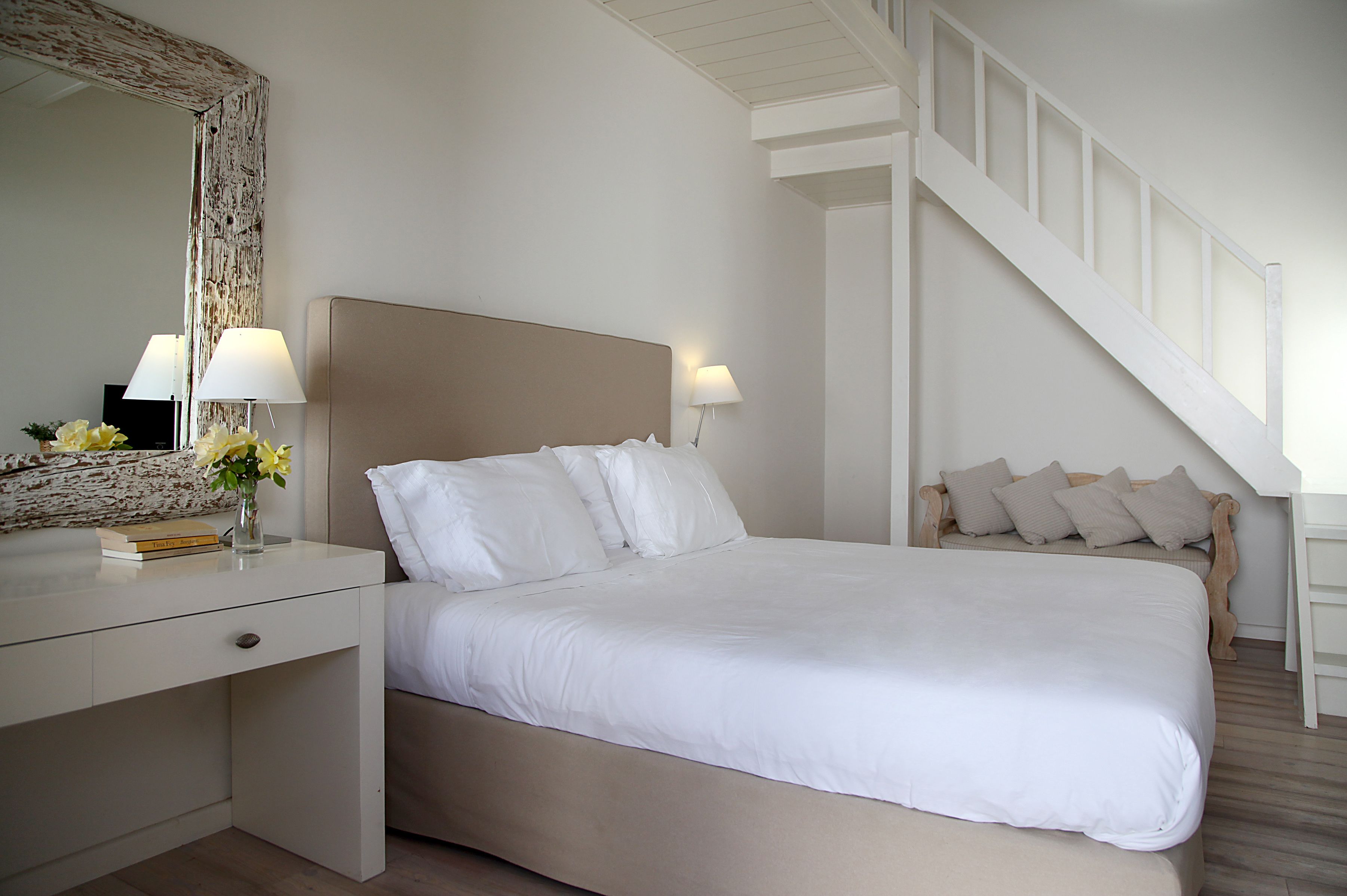 Un dormitorio con cama, mesita de noche, lámpara y una escalera.