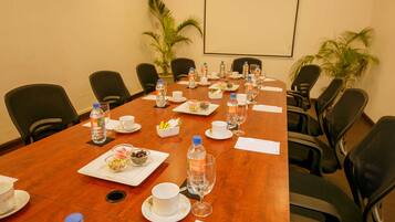 A conference room with a long table set for a meeting, equipped with water bottles, cups, and a small bowl of snacks.