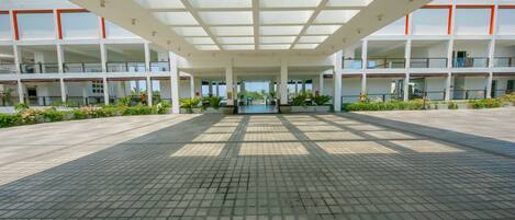 A spacious covered plaza with a grid of columns and a central open area, surrounded by multi-story buildings with balconies.