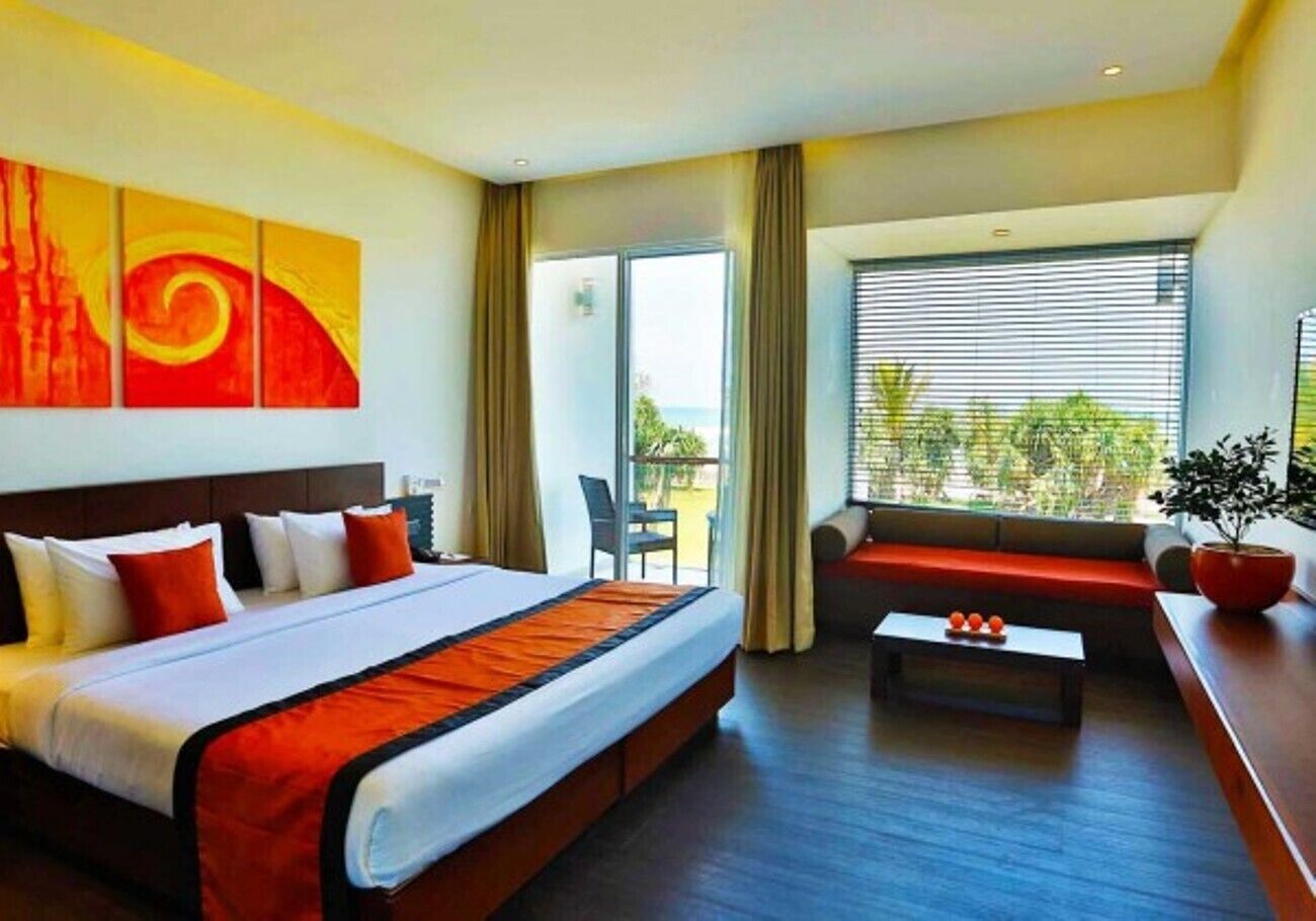 Habitación de hotel con una cama grande, un sofá, una mesita de centro y vistas al exterior.