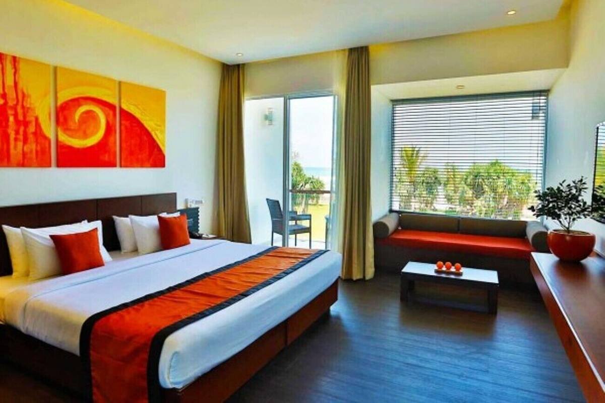 A hotel room with a large bed, a sofa, a coffee table, and a view of the outdoors.