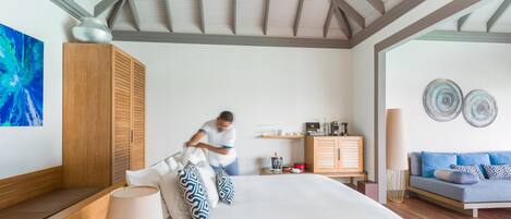 A hotel room with a bed, a wooden wardrobe, a blue sofa, and a ceiling fan.