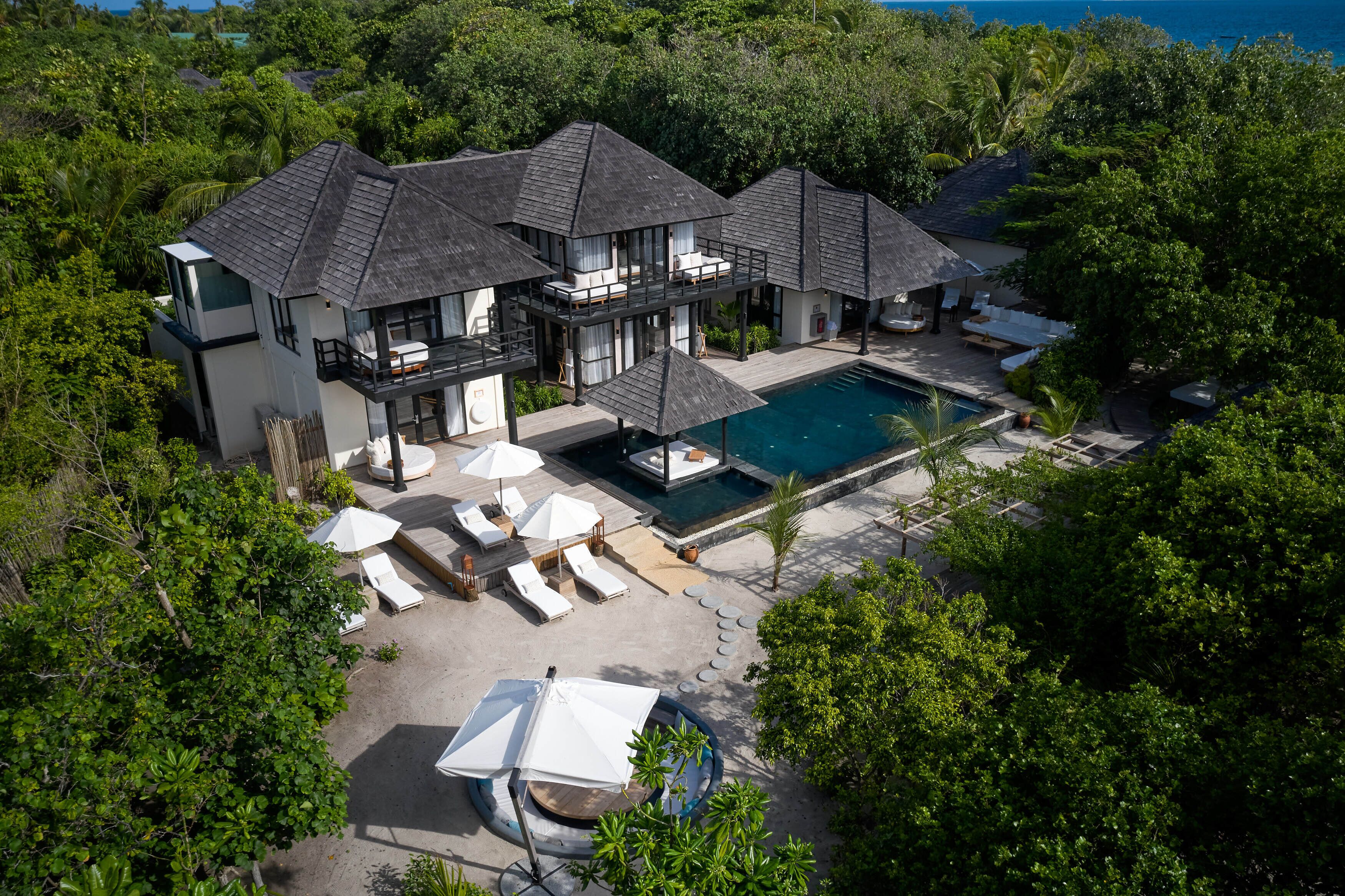 A resort with multiple overwater bungalows, a swimming pool, and outdoor seating areas.