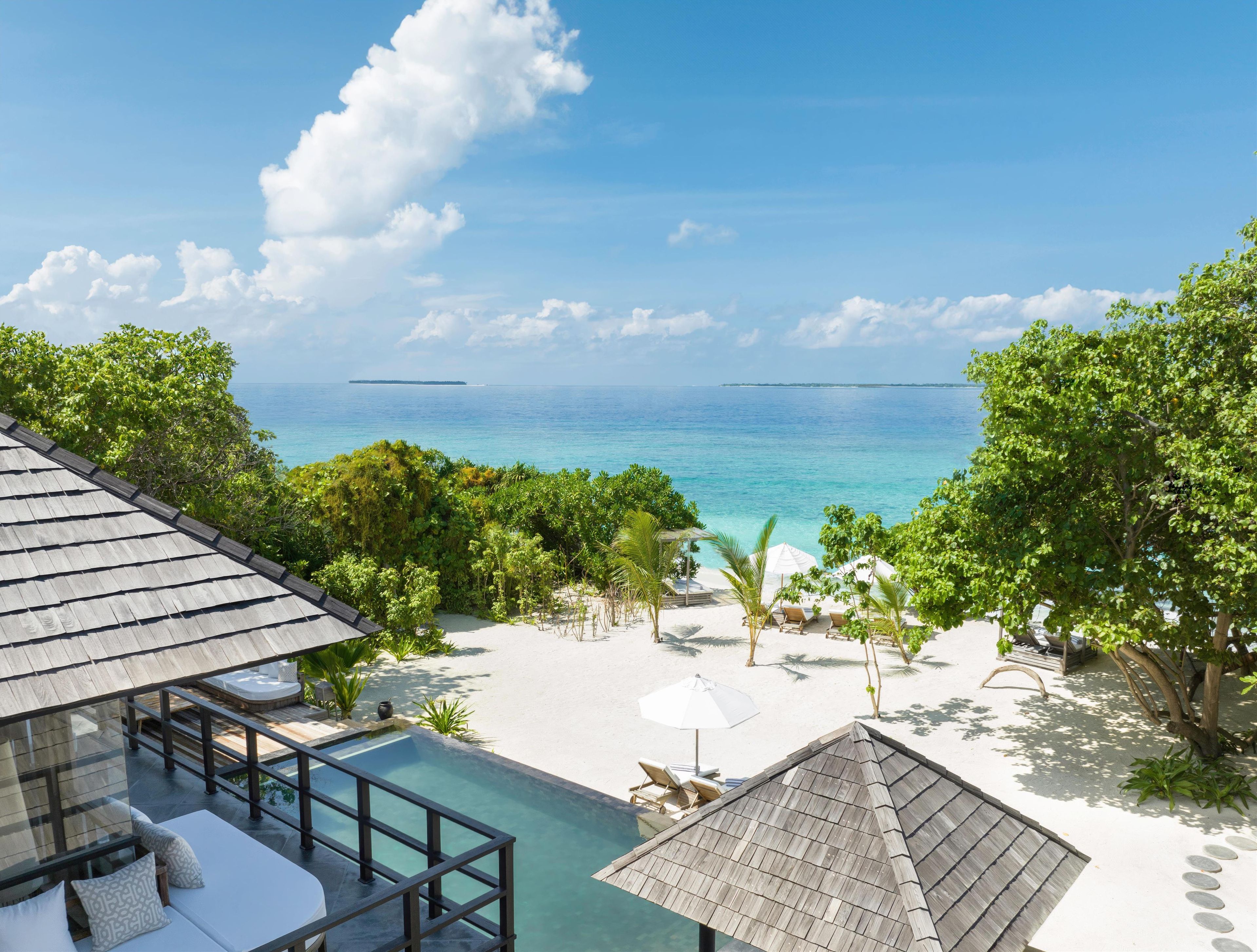 Un resort con piscina, sillas de descanso y vista al océano.