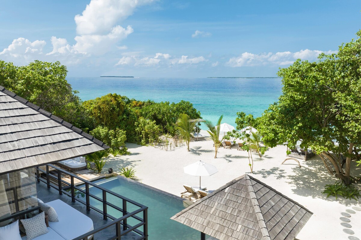 A resort with a pool, lounge chairs, and a view of the ocean.