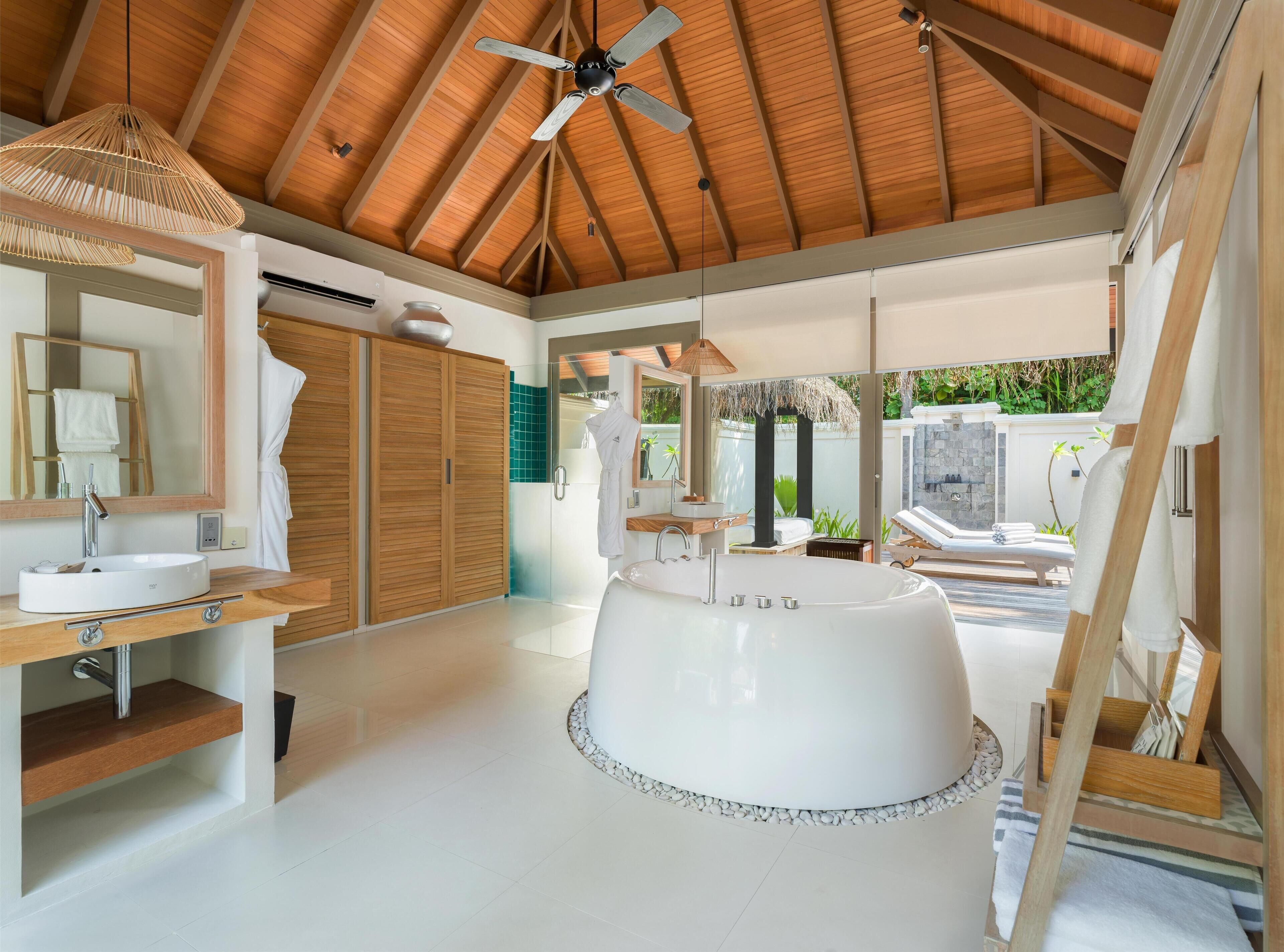 A modern bathroom with a freestanding bathtub, wooden ceiling, and a large mirror.