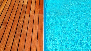 Una piscina al aire libre, sillones reclinables de piscina