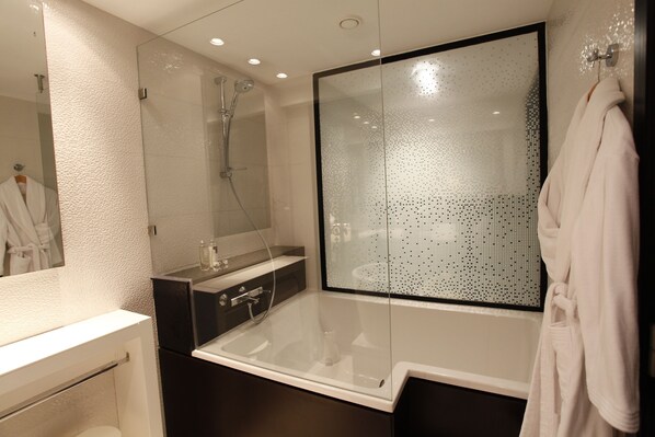 A modern bathroom with a glass-enclosed shower, a bathtub, and a vanity with a mirror.