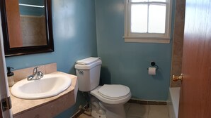 Une salle de bain avec un lavabo, des toilettes et une fenêtre.