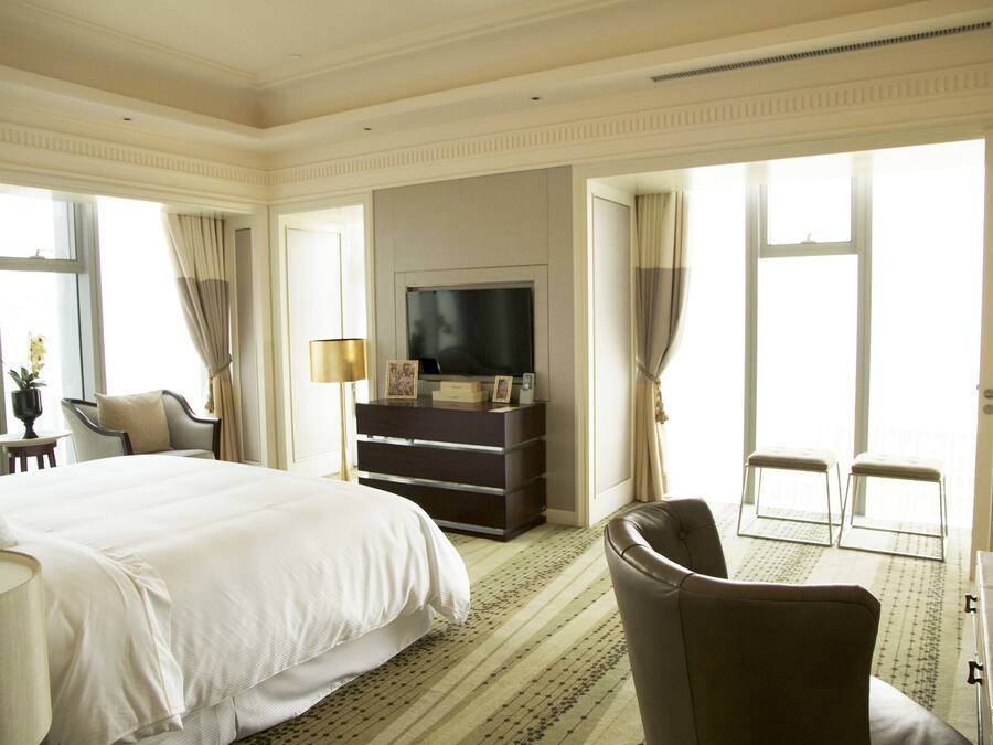 A hotel room with a large bed, a television, a dresser, and two chairs.